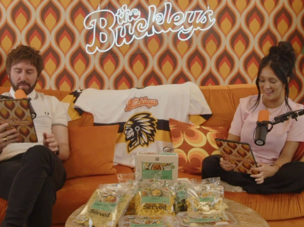 Two people sat on sofa doing podcast